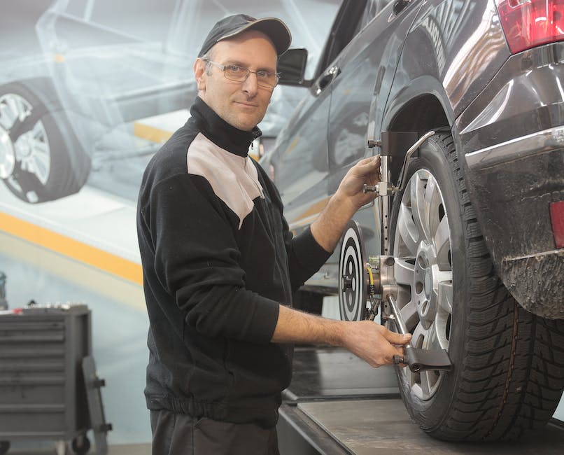 A well-maintained car in a garage with a mechanic checking the oil and tires.